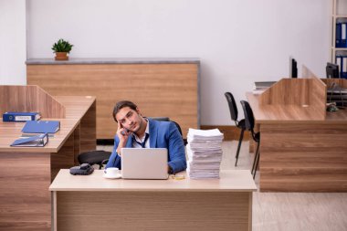 Ofisteki aşırı işten memnun olmayan genç bir erkek işçi.