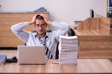 Ofisteki aşırı işten memnun olmayan genç bir erkek işçi.