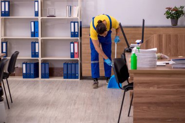 Genç müteahhit ofisi temizliyor.