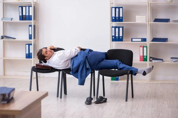 Young male employee sleeping in the office on chairs — Stock Photo, Image