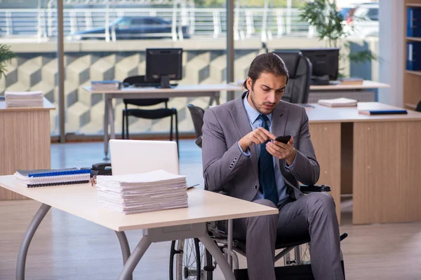 Young male employee in wheel-chair working in the office — Stock Photo, Image