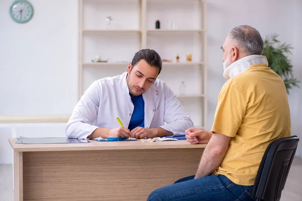 Old neck injured man visiting young male doctor — Stock Photo, Image