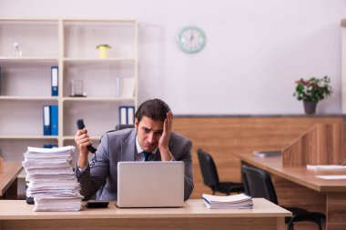 Ofisteki aşırı işten memnun olmayan genç bir erkek işçi.