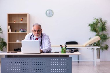 Klinikte çalışan yaşlı erkek doktor.