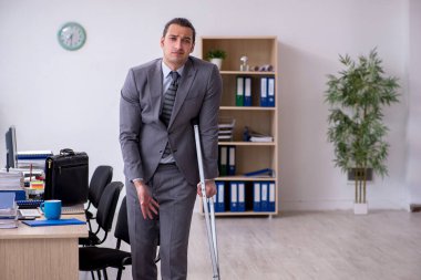 Ofiste çalışan genç bacağı yaralı bir erkek işçi.