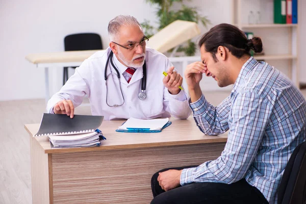 Junge männliche Patientin besucht betagten Arzt — Stockfoto