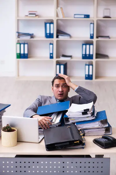 Joven empleado masculino infeliz con el trabajo excesivo — Foto de Stock