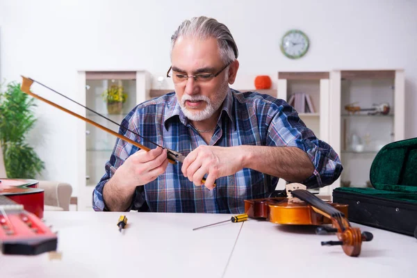Seniorchef repariert Musikinstrumente zu Hause — Stockfoto