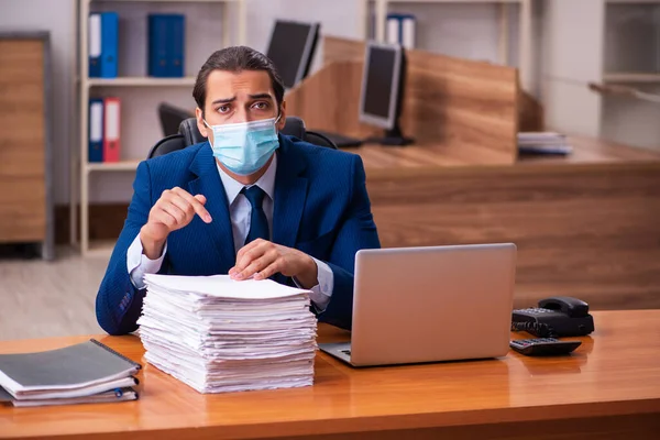 Ung manlig anställd som arbetar på kontoret bär mask — Stockfoto