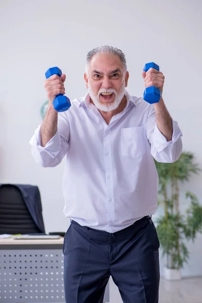 Empleado varón envejecido haciendo ejercicios físicos durante el descanso —  Fotos de Stock