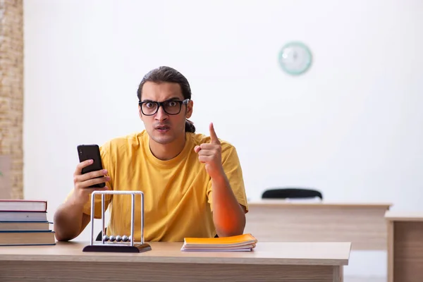 Young male student holding mobile phone during exam preparation — Stock Photo, Image