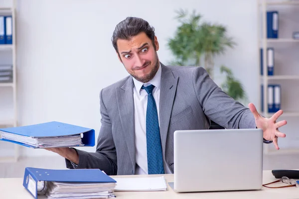 Joven empleado masculino descontento con el trabajo excesivo en la oficina — Foto de Stock