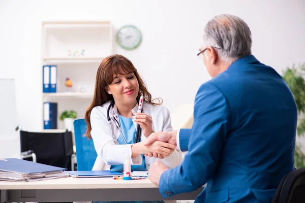 Gammal affärsman besöker ung kvinnlig läkare — Stockfoto