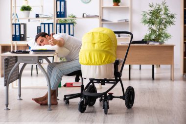 İş yerinde yeni doğan bebeğe bakan genç bir erkek işçi.