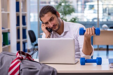 Genç erkek çalışan ofiste spor egzersizleri yapıyor.