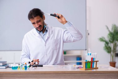 Sınıfta oturan genç erkek kimya öğretmeni.