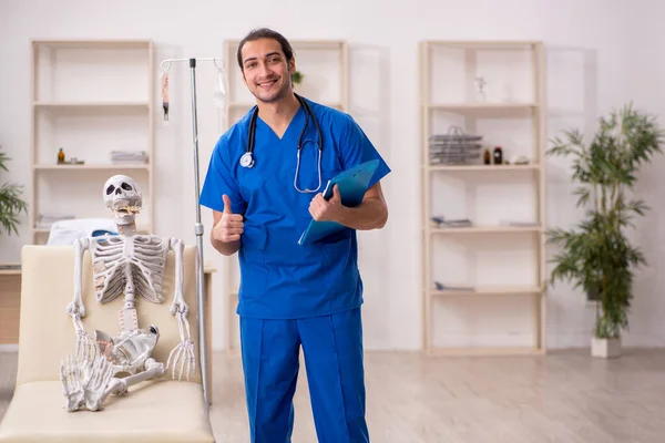 Joven médico masculino sugiriendo pastillas para el paciente esqueleto — Foto de Stock