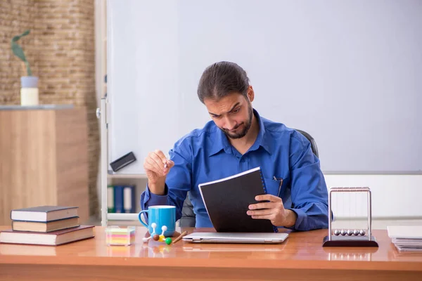 Νεαρός φυσικός δάσκαλος κάθεται στην τάξη — Φωτογραφία Αρχείου