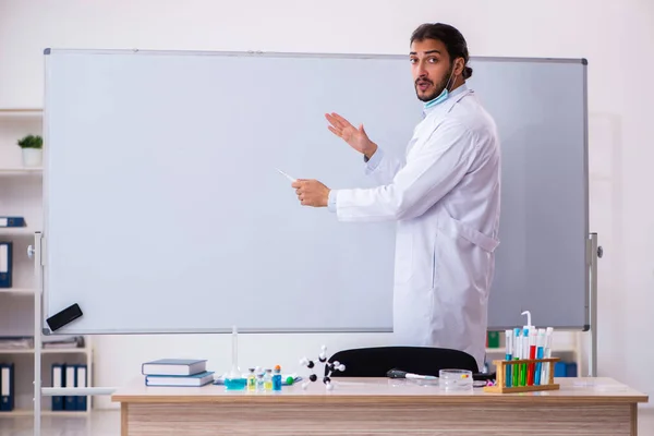 Mladý muž chemik učitel sedí ve třídě — Stock fotografie