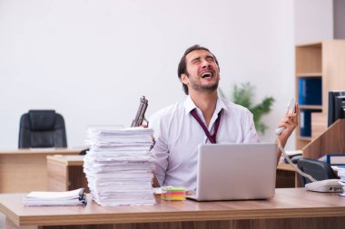 Ofisteki aşırı işten memnun olmayan genç bir erkek işçi.