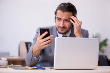 Ofisteki aşırı işten memnun olmayan genç bir erkek işçi.