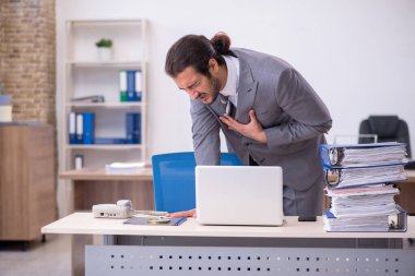 Ofisteki aşırı işten memnun olmayan genç bir erkek işçi.