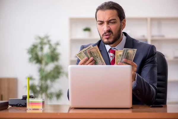 Junge männliche Angestellte mit Geldscheinen im Büro — Stockfoto