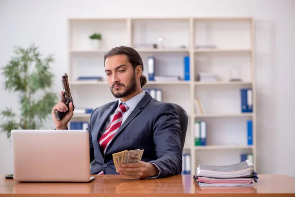 Mladý muž zaměstnanec drží zbraň a bankovky v bankrotu conc — Stock fotografie