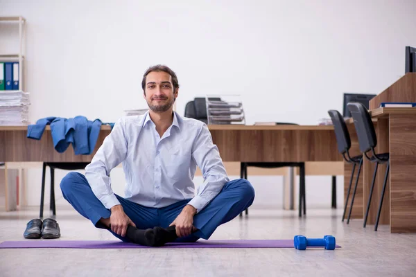 Young male employee doing sport exercises during break — Stock Photo, Image