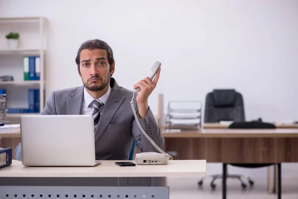 Giovane dipendente maschio infelice con un lavoro eccessivo in ufficio — Foto Stock