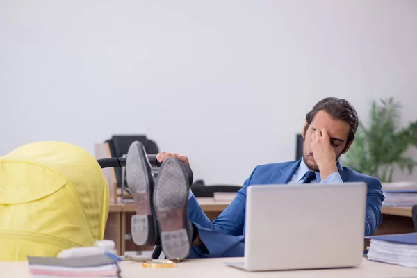 Ung manlig anställd som tar hand om nyfödda på arbetsplatsen — Stockfoto