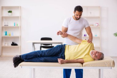 Yaşlı erkek hasta, genç erkek doktor masörünü ziyaret ediyor.