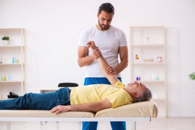 Yaşlı erkek hasta, genç erkek doktor masörünü ziyaret ediyor.