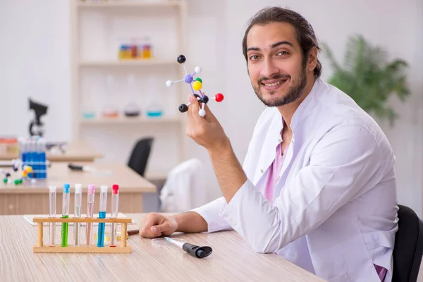 Mladý chemik sedící za stolem ve třídě — Stock fotografie