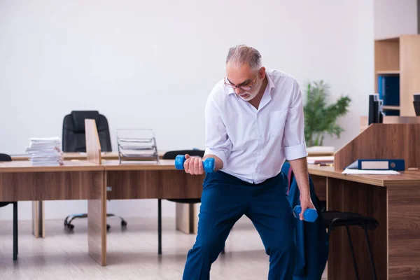 Gammal affärsman anställd gör sport övningar på kontoret — Stockfoto