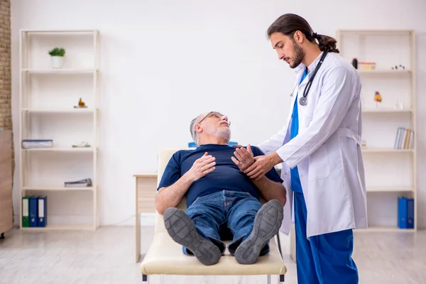 Stary mężczyzna pacjent odwiedzający młody mężczyzna lekarz kręgarz — Zdjęcie stockowe