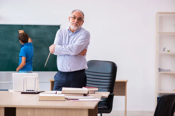 Oude mannelijke leraar en schooljongen in de klas — Stockfoto