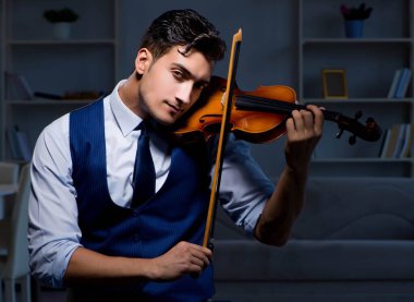 Genç müzisyen evde keman çalıyor.
