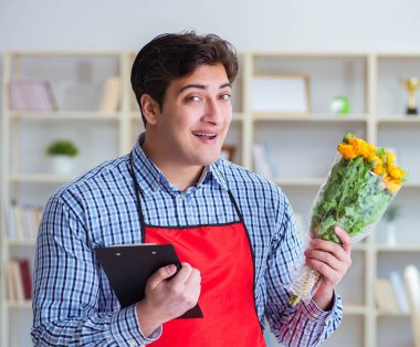 Çiçekçi asistanı bir demet çiçek veriyor.