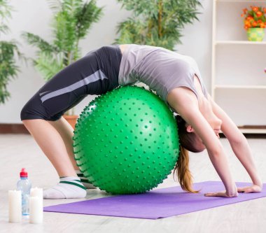 Spor salonunda denge topuyla egzersiz yapan genç bir kadın.