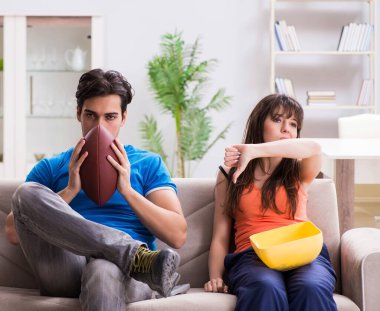 Adam karısıyla Amerikan futbolu seyrediyor.