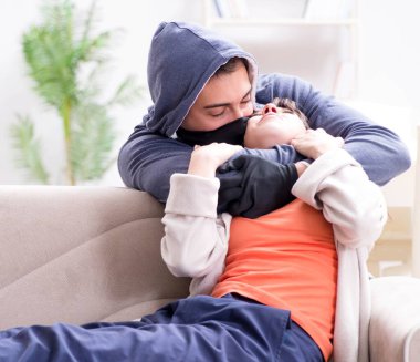 Silahlı bir adam evde genç bir kadına saldırıyor.