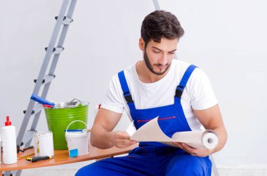 Tamirci, duvar kağıdıyla evde tadilat yapıyor.