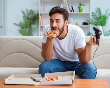 Pizza yiyen adam evde yemek yiyor, dinleniyor.