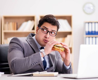 Aç komik iş adamı abur cubur sandviç yiyor.