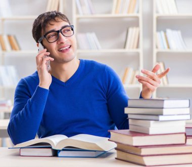 Erkek öğrenci üniversite kütüphanesinde sınava hazırlanıyor.