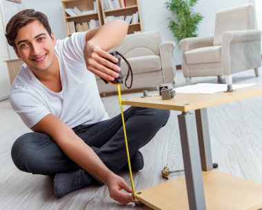 Adam evde mobilya montajı yapıyor.