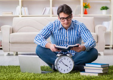 Genç yakışıklı adam evde yerde oturuyor.