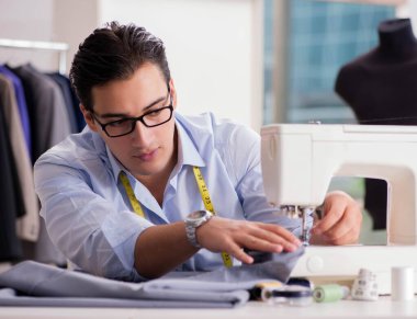 Genç terzi yeni elbiseler üzerinde çalışıyor.