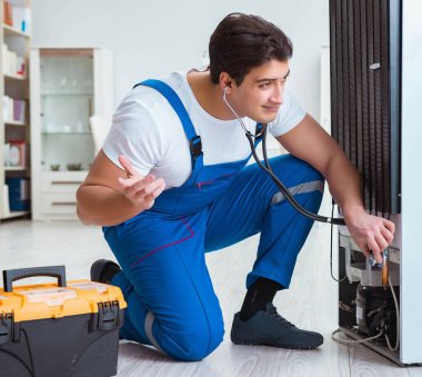 Tamirci müteahhit DIY konseptinde buzdolabını tamir ediyor.